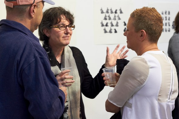 Solander Gallery NZ Director, Paulette Robinson, chatting in front of prints by Michael Kempson